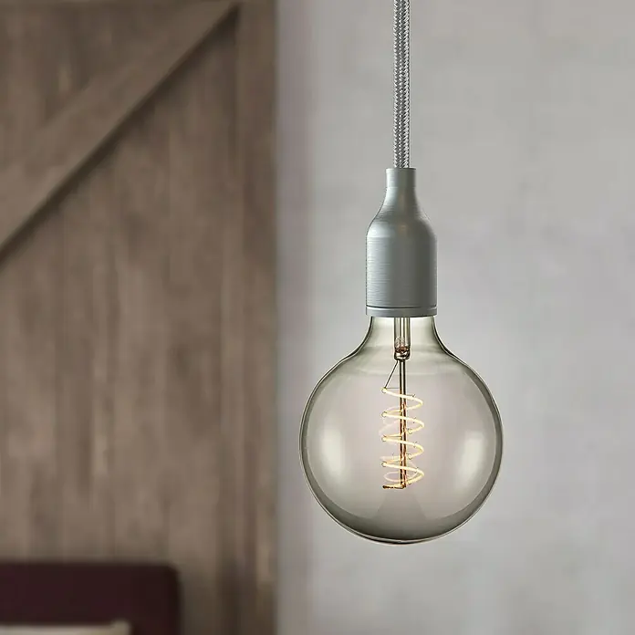 Home Sweet Home LED-Lampe Vintage Globe-Form E27 - E27, Dimmbar, Warmweiß, 140 lm, 4 W - Nahaufnahme einer dekorativen Glühbirne mit Wendelfaden, die an einem geflochtenen Kabel von der Decke hängt und ein warmes Licht ausstrahlt.