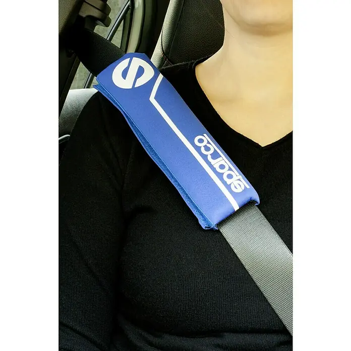 Sparco Almohadillas para cinturón de seguridad - Apto para: Coches, 2 ud. - Primer plano de una persona que lleva un protector de cinturón azul Sparco sobre el cinturón, con un logotipo blanco y detalles para mayor comodidad.