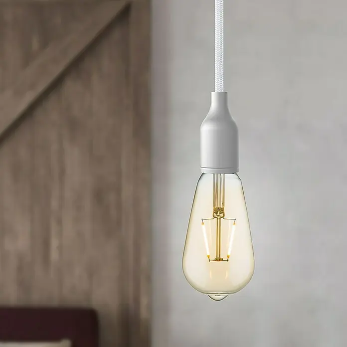 Home Sweet Home LED-Lampe - E27, Nicht Dimmbar, Warmweiß, 160 lm, 2 W, Farbe: Gold - Nahaufnahme einer hängenden Edison-Glühbirne mit warmem Licht und weißem Kabel vor verschwommenem Hintergrund.