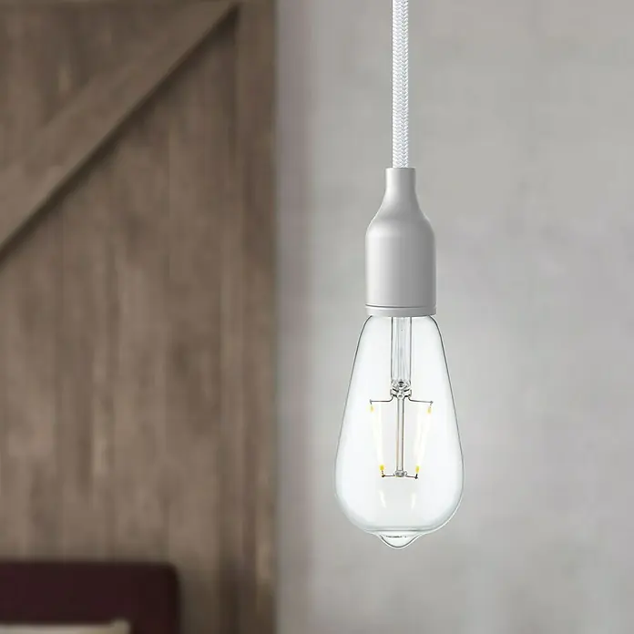 Home Sweet Home LED-Lampe - E27, Nicht Dimmbar, Neutralweiß, 160 lm, 2 W, Farbe: Klar - Nahaufnahme einer Vintage-Glühbirne mit grauem Sockel und gewebtem Kabel, die ein warmes Licht ausstrahlt und eine gemütliche Atmosphäre schafft.