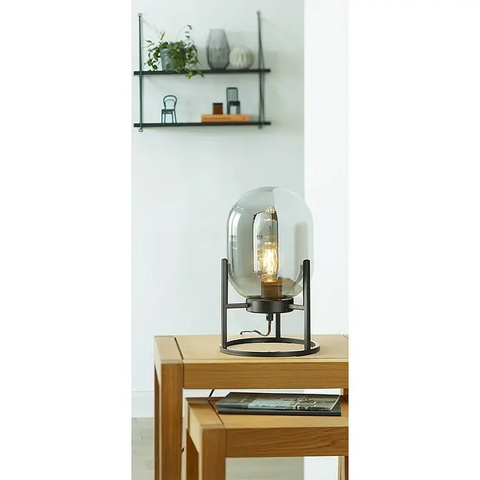 Fischer & Honsel Tischleuchte - L x B x H: 5 x 17 x 8 cm, Schwarz, E27 - Nahaufnahme einer modernen Tischleuchte mit einem grauen Glasschirm und einem schwarzen Metallgestell, die auf einem Holzbeistelltisch steht.