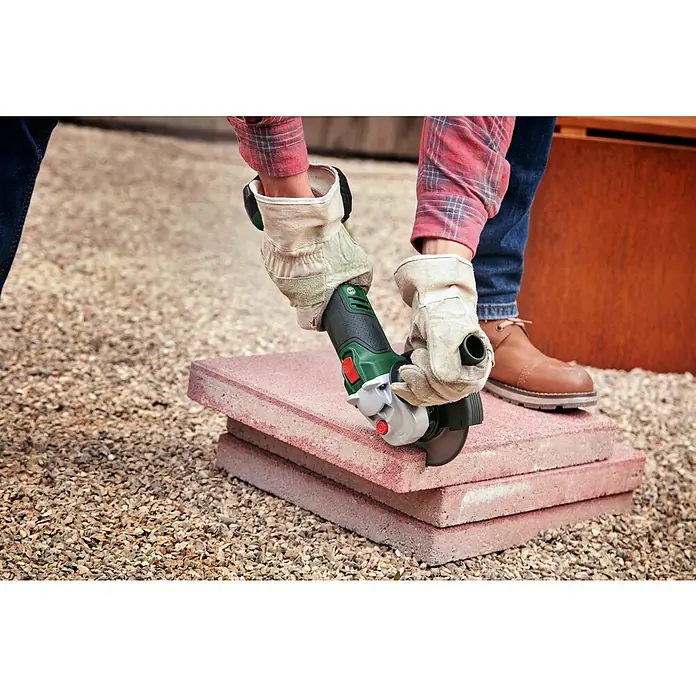 Bosch Power for All 18V Akku-Winkelschleifer UniversalGrind 18V-75 - Ohne Akku, Durchmesser Scheibe: 125 mm - Eine Person, die mit einer Bosch-Flex Winkelschleifer ein Pflasterstein schneidet, mit Schutzhandschuhen und robuster Arbeitskleidung.