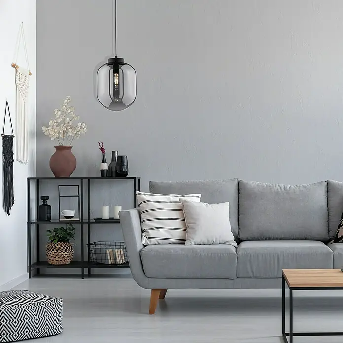 Fischer & Honsel Pendelleuchte - 40 W, L x B x H: 110 x 28 x 28 cm, E27 - Eine moderne Wohnzimmeraufnahme mit einer stilvollen Hängelampe mit rauchfarbenem Glas über einem grauen Sofa und einem Regal.