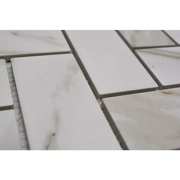 Mosaikfliese Fischgrät Calacatta CIM HB CT - 27,9 x 27,4 cm, Weiß, Matt - Nahaufnahme von weißen Marmorfliesen mit subtilen Maserungen, die ein elegantes Muster für Badezimmer oder Küchenrückwände bilden.
