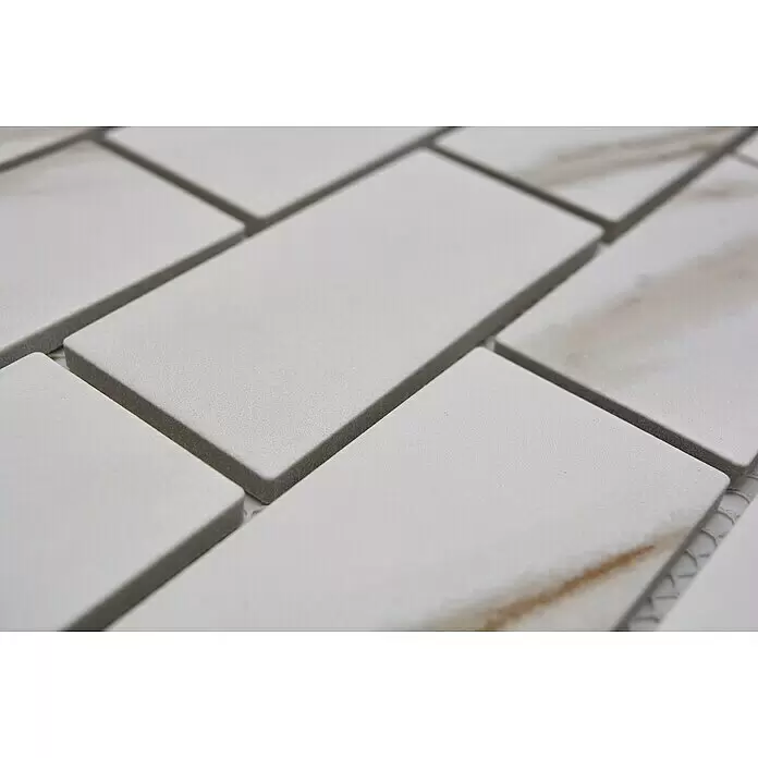 Mosaikfliese Brick Calacatta CIM BR CT - 29,1 x 29,5 cm, Weiß, Matt - Nahaufnahme von weißen rechteckigen Fliesen mit subtiler brauner Maserung, im Ziegelmuster angeordnet.