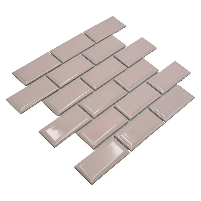 Mosaikfliese Metro Uni CG M19TR - 29,1 x 29,6 cm, zartrosa, Glänzend - Nahaufnahme eines Musters aus beigen, glänzenden U-Bahn-Fliesen auf einer schwarzen Oberfläche, ideal für Küchendekor oder Badezimmerakzente.