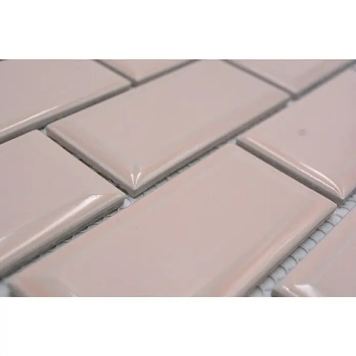 Mosaikfliese Metro Uni CG M19TR - 29,1 x 29,6 cm, zartrosa, Glänzend - Nahaufnahme von rosa, rechteckigen Metrofliesen mit abgerundeten Kanten, die versetzt angeordnet sind. Ideal für moderne Wandgestaltungen.