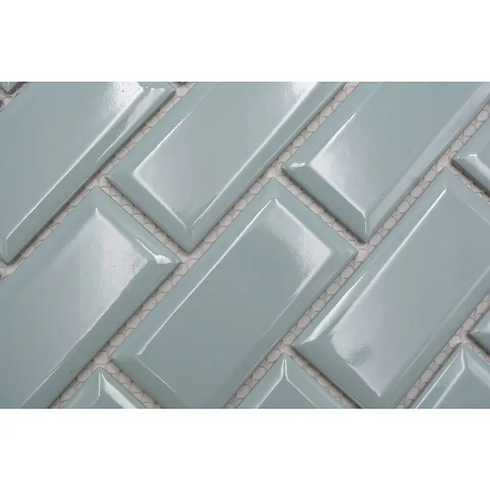 Mosaikfliese Metro Uni CG M17MG - 29,1 x 29,6 cm, mintgrün, Glänzend - Nahaufnahme von hellblauen, rechteckigen Fliesen in einem Fischgrätenmuster, die ein modernes und stilvolles Designelement zeigen.