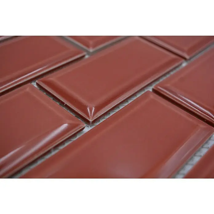 Mosaikfliese Metro Uni CG M11R - 29,1 x 29,6 cm, rot, Glänzend - Nahaufnahme von glänzenden, ziegelroten Subway-Fliesen, die in einem versetzten Muster angeordnet sind und ein elegantes Designelement für jede Wand bieten.