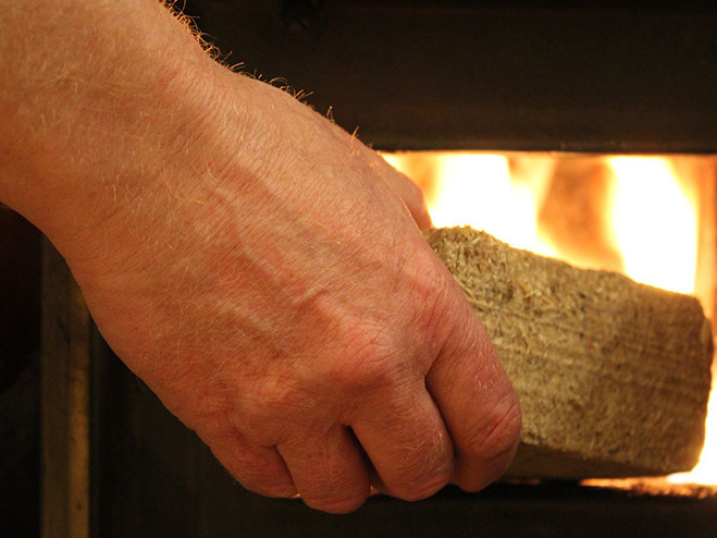 Holzbrikett wird in Ofen gelegt
