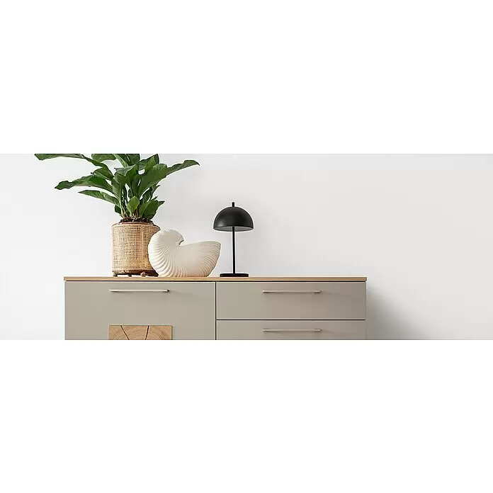 SCHÖNER WOHNEN-Farbe Naturell Lehm-Streichputz Streich-Lehmputz - Weiß, 8 kg - Graue Kommode mit heller Holzplatte, Metallgriffen und dekorativer Holzverkleidung, dekoriert mit Pflanze, Muschel und Lampe.