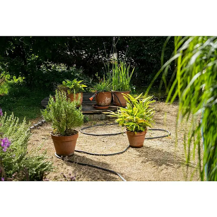 Gardena Gartenschlauch Liano Life - 10 m, Schlauchdurchmesser: 13 mm - Verschiedene Topfpflanzen und ein Bewässerungsschlauch im Garten, der die Pflanzen mit Wasser versorgt. Die Pflanzen sehen gesund und gepflegt aus.