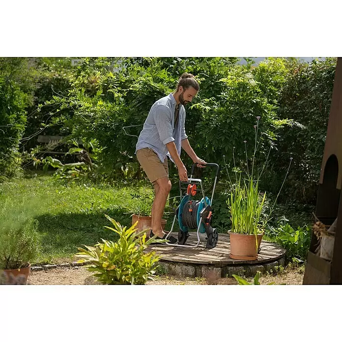 Gardena Gartenschlauch Liano Life Set - 30 m, Schlauchdurchmesser: 13 mm - Mann im Garten nutzt einen blau-schwarzen Schlauchwagen, um einen Gartenschlauch zu bedienen.