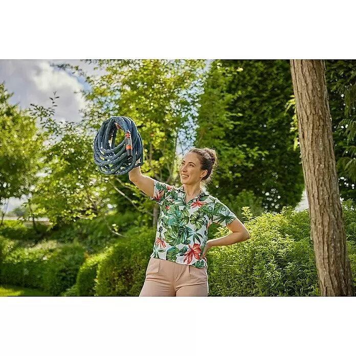 Gardena Gartenschlauch Liano Life Set - 30 m, Schlauchdurchmesser: 13 mm - Frau hält einen aufgerollten blauen Gartenschlauch mit orangefarbenen Anschlüssen.
