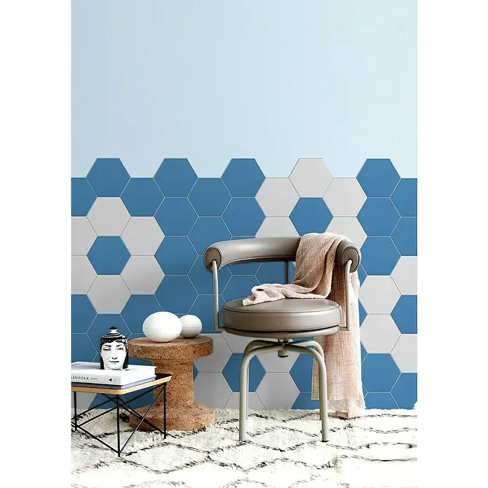 Selbstklebemosaik Hexagon Uni SAMT CHA3B - 15,2 x 17,2 cm, Blau, Matt - Ein stilvoller Raum mit einem grauen Drehstuhl, einer dekorativen Wand mit blauen und weißen Sechseckfliesen und einem flauschigen Teppich.