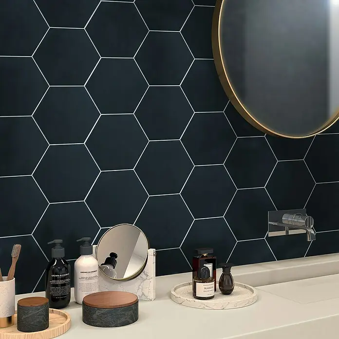 Selbstklebemosaik Hexagon Uni SAMT CHA4BL - 15,2 x 17,2 cm, Schwarz, Matt - Elegantes Badezimmer-Interieur mit hexagonalen Fliesen und hochwertigen Pflegeprodukten auf einem minimalistischen Waschtisch.