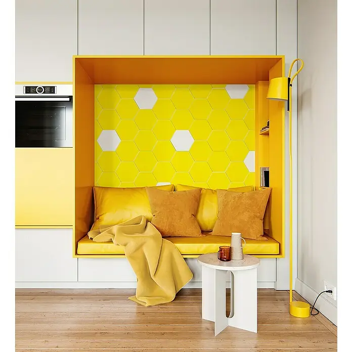 Selbstklebemosaik Hexagon Uni SAMT CHA2Y - 15,2 x 17,2 cm, Gelb, Matt - Helles Wohnzimmer mit gelber Sitzecke, gelber Stehlampe und einem weißen Beistelltisch. Die Sitzecke ist mit Kissen und einer Decke ausgestattet.