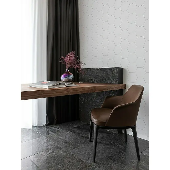 Selbstklebemosaik Hexagon Uni SAMT CHA5W - 15,2 x 17,2 cm, Weiß, Matt - Elegantes Interieur mit einem braunen Lederstuhl vor einem Schreibtisch mit Blumenvase und Buch, ergänzt durch dunkle Vorhänge und hexagonale Wandfliesen.