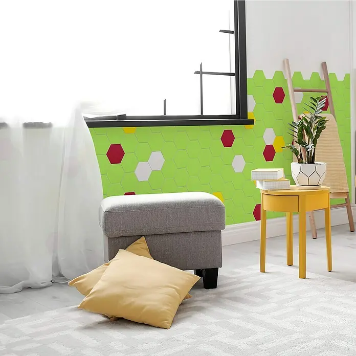 Selbstklebemosaik Hexagon Uni SAMT CHB5G - 15,2 x 17,2 cm, Grün, Matt - Ein stilvolles Interieur mit einem grauen Hocker, gelbem Beistelltisch und dekorativen Wandpaneelen mit bunten Hexagonen.