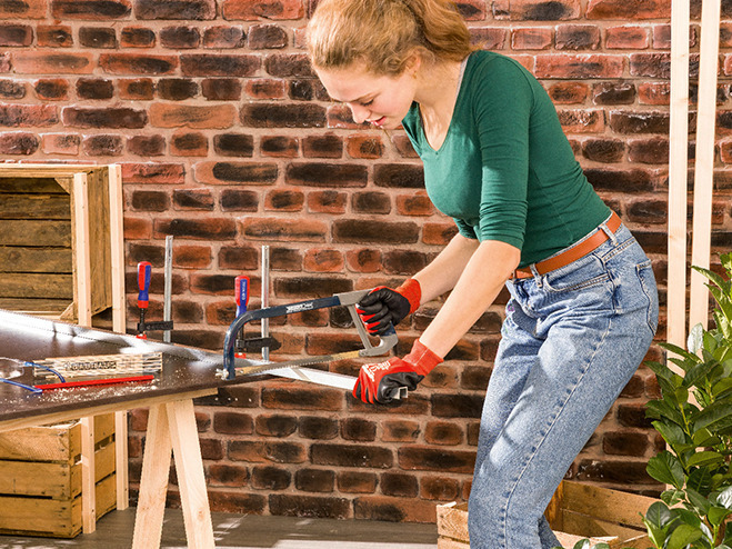 Eine Frau mit Metallsäge sägt Schienen zu