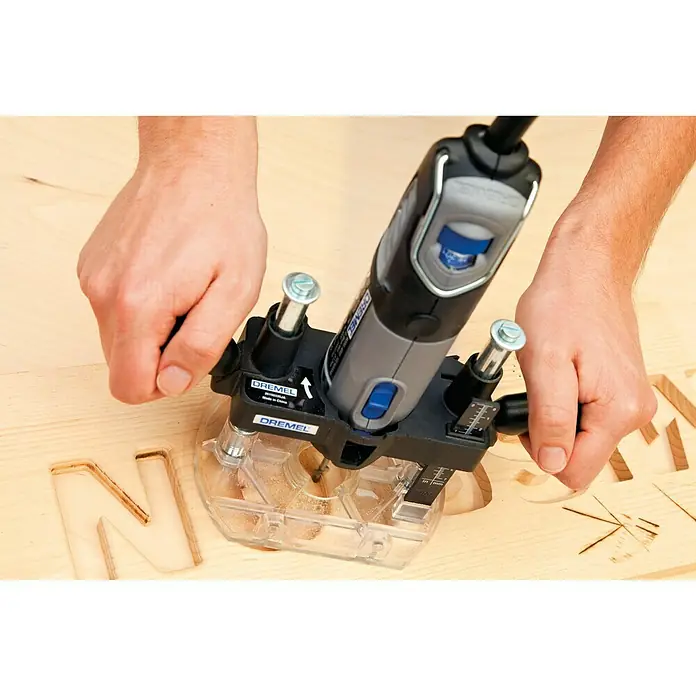 Dremel Oberfräsenvorsatz 335 - Oberfräsenvorsatz, Kantenführung, Kreisführung, Schablonenführung, Schlüssel - Nahaufnahme des Dremel Fräs-Vorsatzes im Einsatz beim Ausfräsen von Buchstaben in Holz. Präzision und Vielseitigkeit für Holzarbeiten.