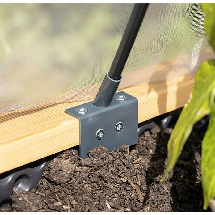 Windhager Folientunnel Komplettset - Passend für: Hochbeete, Einsatzbereich: Garten - Nahaufnahme eines Gewächshausrahmens aus Holz mit Metallbeschlägen, der in dunkler Erde verankert ist. Das Bild zeigt die Detailgenauigkeit der Konstruktion.