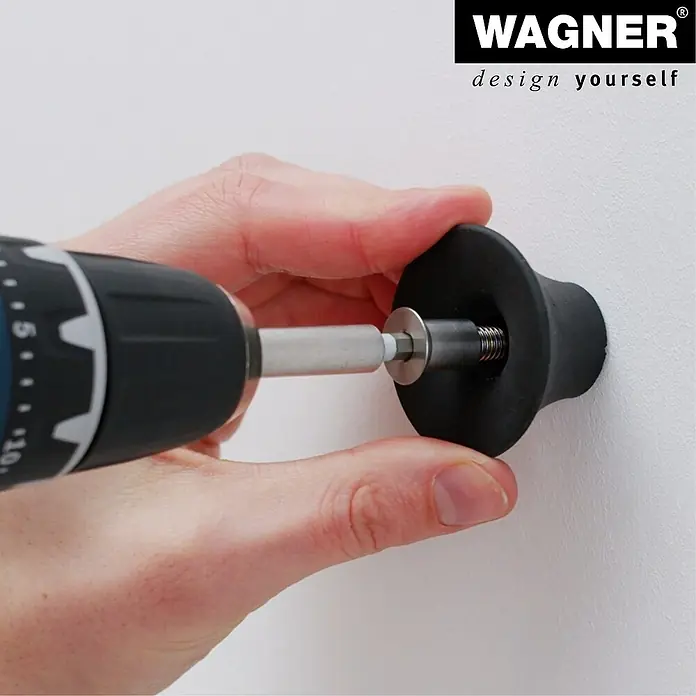 Wagner System Garderobenhaken-Set - Ø x H: 50 x 30 mm, Schwarz, 4 Stk. - Eine Person befestigt einen schwarzen Möbelknopf mit einer Schraube und einem Schraubenzieher an einer weißen Wand.