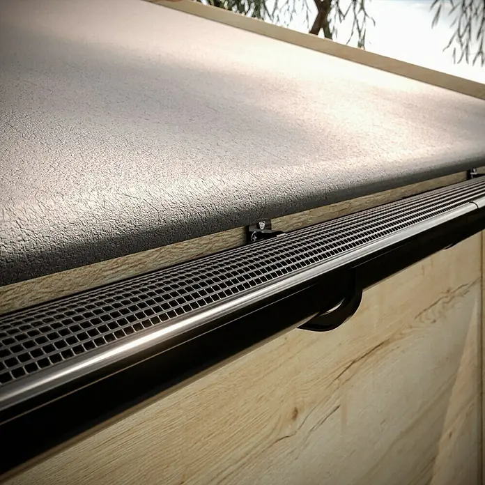 Marley Dachrinne - Nennweite: 75 mm, Länge: 200 cm, Kunststoff, Anthrazit-Metallic - Nahaufnahme einer Dachrinne mit Schutzgitter, montiert an einem Holzgebäude. Das Gitter verhindert das Verstopfen durch Laub.
