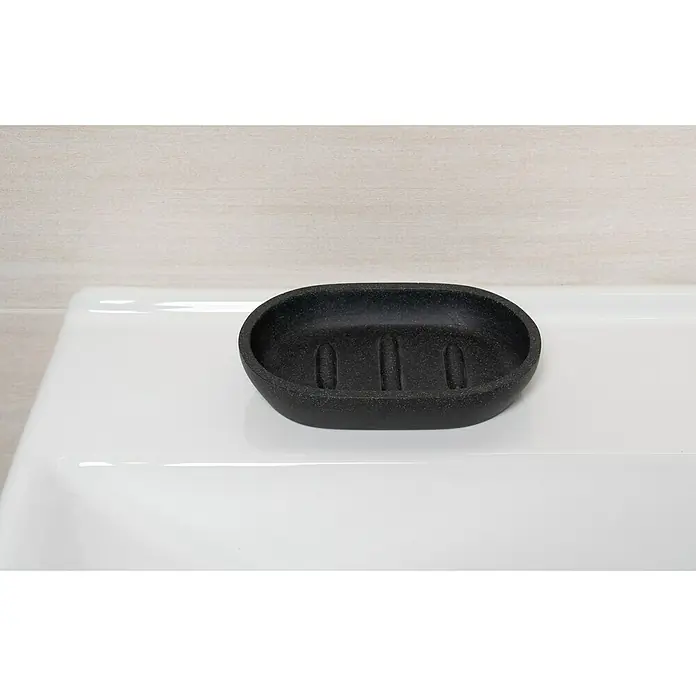 Camargue Seifenschale Stone - Polyresin, Anthrazit, Länge: 13,1 cm - Eine ovale, schwarze Seifenschale mit Rillen liegt auf einer weißen Oberfläche. Sie ist schlicht und funktional gestaltet.