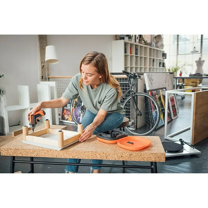 Black+Decker Atornillador de batería BCF611CK-QW - 3,6 V, 1 batería - Mujer montando un mueble de madera en un taller con un destornillador inalámbrico Black+Decker.