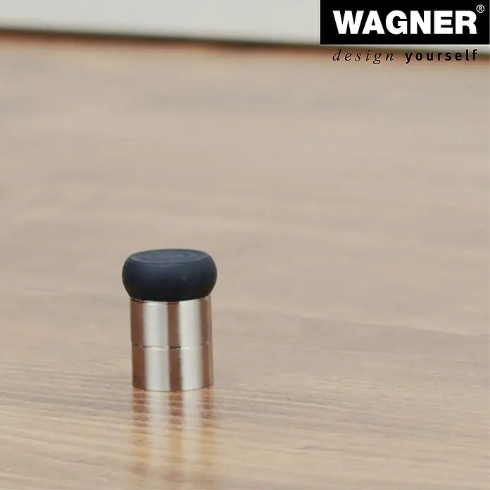 Wagner System Wandtürstopper EH5114 - 1 Stk., Edelstahl-Optik - Nahaufnahme eines Türstoppers aus Metall mit schwarzem Gummipuffer auf einem Holzboden.
