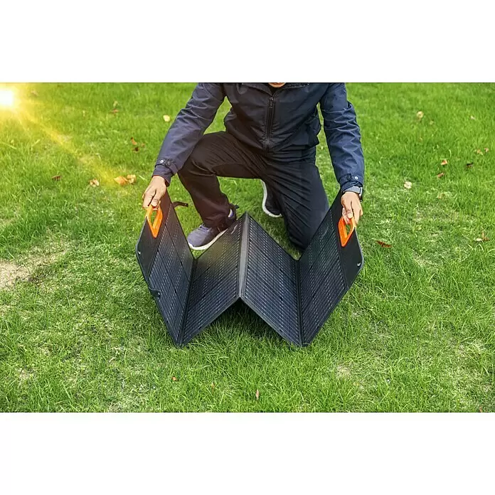 Yard Force Set Powerstation LX PS600 + Solarmodul Flex LX SPP20 - 518 Wh - Person richtet ein schwarzes faltbares Solarpanel mit orangen Griffen ein.