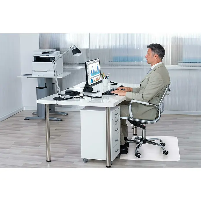Alfombra protectora - Blanco, 90 x 90 cm - Un hombre está sentado en un escritorio con una computadora y un protector de suelo debajo.