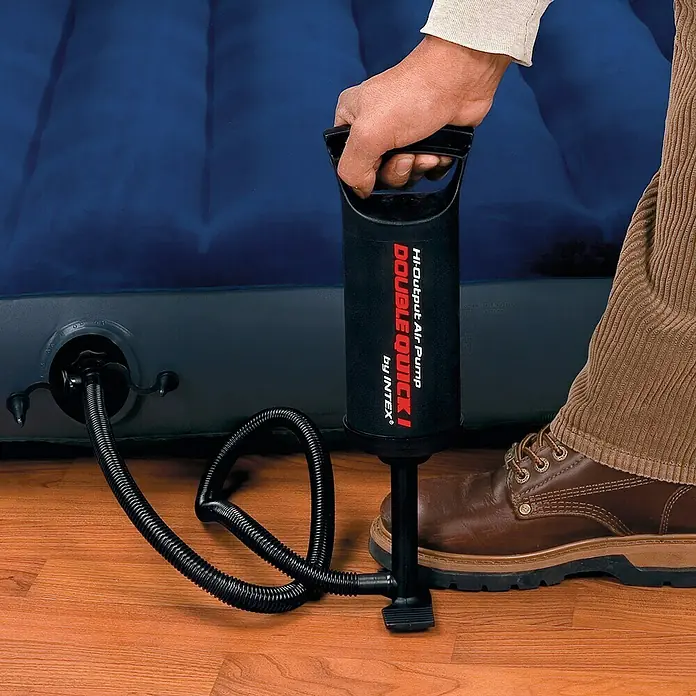 Intex Bomba de aire doble velocidad - Apto para: Equipos de soplado - Imagen de una persona inflando un colchón de aire con una bomba manual rápida doble de Intex, centrándose en la bomba.