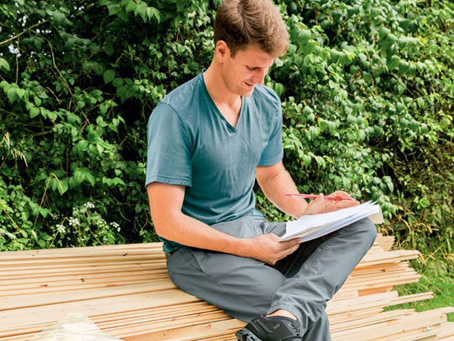 Mann studiert Aufbauanleitung für ein Gartenhaus