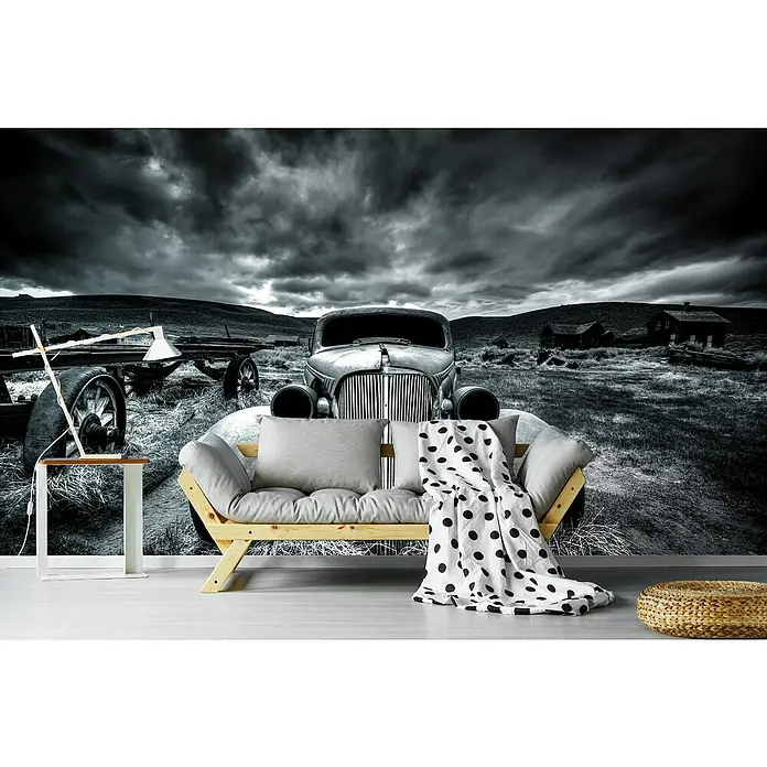 Papermoon Premium collection Fototapete Um zu Fahren - B x H: 250 x 186 cm, Vlies - Detailaufnahme einer Holzbettcouch mit Kissen und einer schwarz-weiß gepunkteten Decke vor einer Wandtapete mit Oldtimer-Motiv.