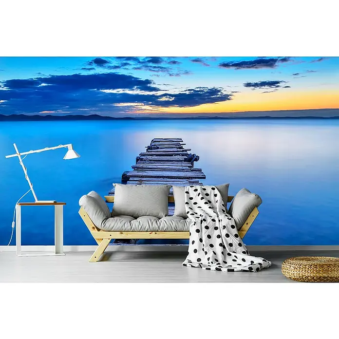 Papermoon Premium collection Fototapete Seebrücke - B x H: 500 x 280 cm, Vlies - Produktfoto mit Wandbild eines Stegs über einem ruhigen See, Sofa mit Decke und Lampe.