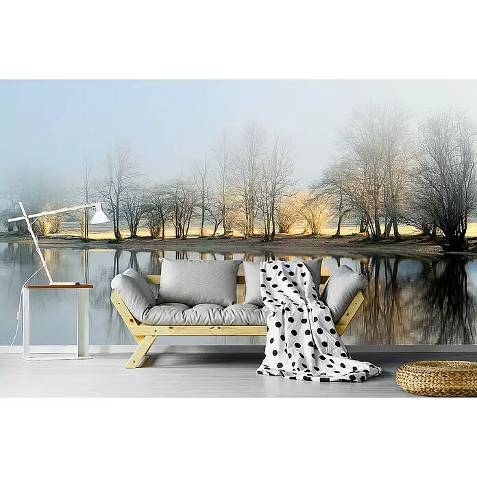 Papermoon Premium collection Fototapete Januarmorgen - B x H: 500 x 280 cm, Vlies - Hölzernes Futonsofa mit hellgrauen Kissen und einer schwarz-weiß gepunkteten Decke, vor einer Wandmalerei mit nebligem Wintersee.