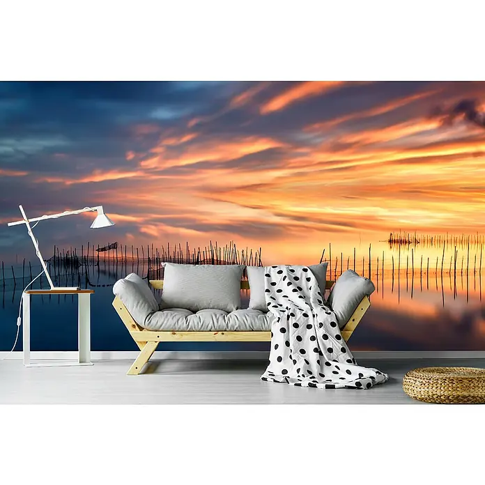 Papermoon Premium collection Fototapete Fishnetten - B x H: 300 x 223 cm, Vlies - Dieses Bild zeigt ein stilvolles Interieur mit einem hellen Sofa und einem Beistelltisch, das vor einer Tapete mit einem friedlichen Sonnenuntergang steht.