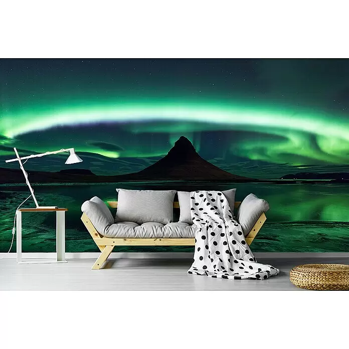 Papermoon Premium collection Fototapete Kirkjufell Aurora - B x H: 200 x 149 cm, Vlies - Holzbettsofa mit hellen Kissen, gepunkteter Decke und Lampe in einem Zimmer mit lebhaftem Nordlichter-Wandbild.