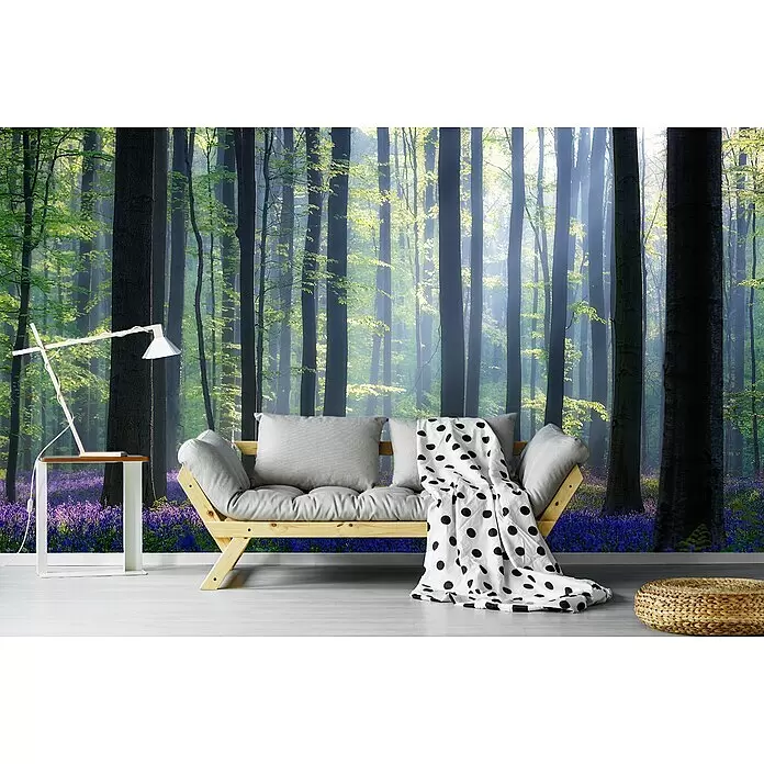 Papermoon Premium collection Fototapete Blauer Blumenwald - B x H: 450 x 280 cm, Vlies - Helles Holzsofa mit grauen Kissen und weißer Tupfendecke in einem Raum mit Waldtapete.