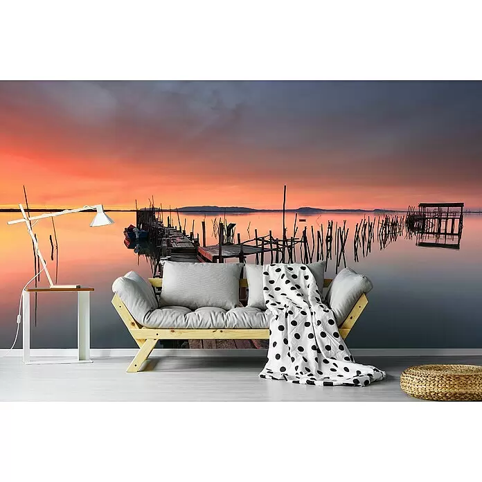 Papermoon Premium collection Fototapete Steg früh am Morgen - B x H: 500 x 280 cm, Vlies - Holzbettsofa mit hellgrauen Kissen und schwarz-weiß gepunkteter Decke.