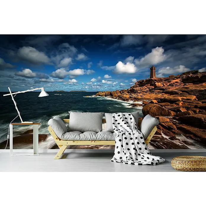 Papermoon Premium collection Fototapete Steiniger Küstenausblick - B x H: 350 x 260 cm, Vlies - Wandbild mit Küstenlandschaft als Hintergrund für ein Sofa mit Kissen und Decke im Wohnzimmer.