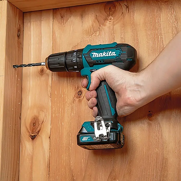 Makita Taladro atornillador percutor de batería HP333DSAE - 12 V, 1 batería, 2 Ah, 30 Nm - Un taladro inalámbrico Makita en acción, perforando madera. Esta herramienta combina potencia y precisión para varias aplicaciones.