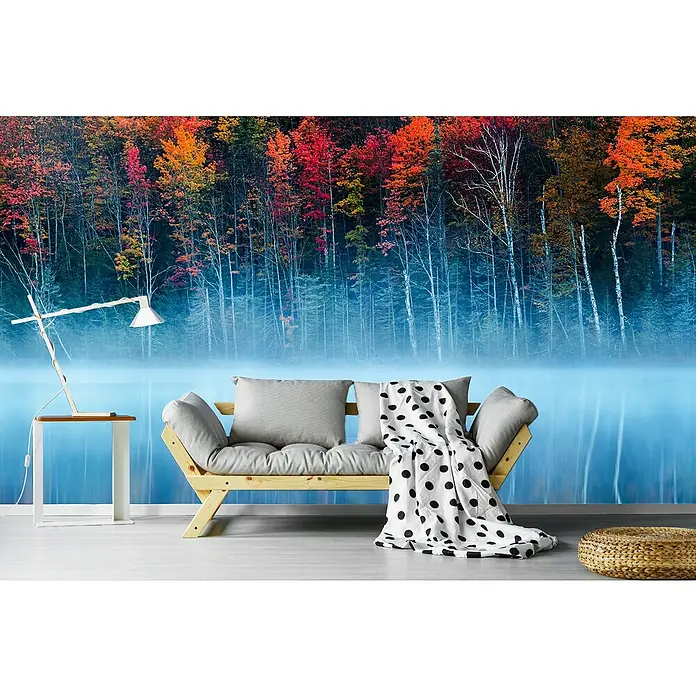Papermoon Premium collection Fototapete See umhüllt im Morgentau - B x H: 350 x 260 cm, Vlies - Ein gemütliches Interieur mit einem stilvollen Sofa, einer Lampe und einem dekorativen Hocker vor einer Tapete mit Herbstwaldmotiv.