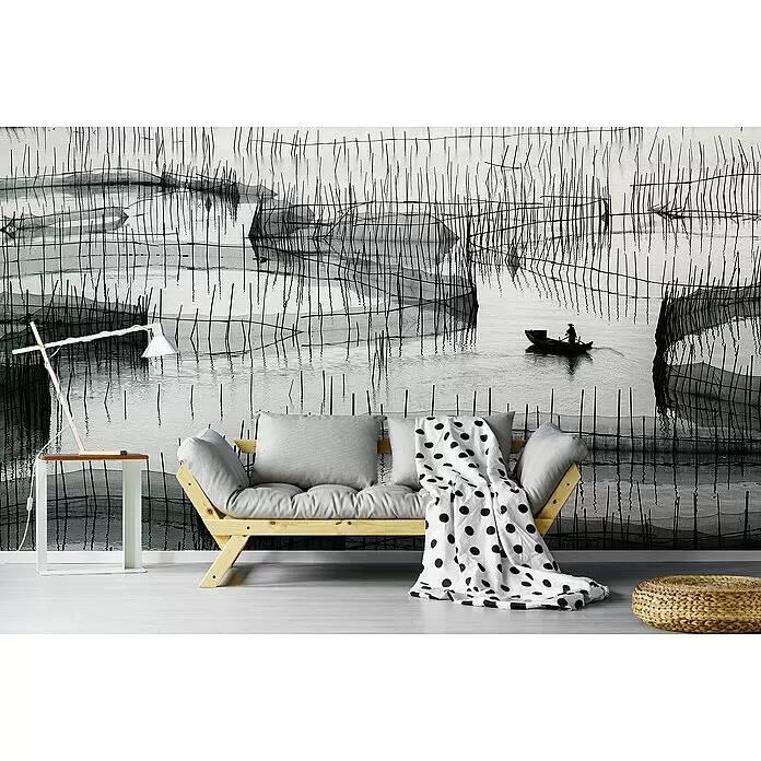 Papermoon Premium collection Fototapete Warten auf den Haken - B x H: 500 x 280 cm, Vlies - Schwarz-weißes Wandbild: ruhiges Wasser, Fischer im Boot und vertikale Netze. Installiert hinter einem hellen Holzsofa.