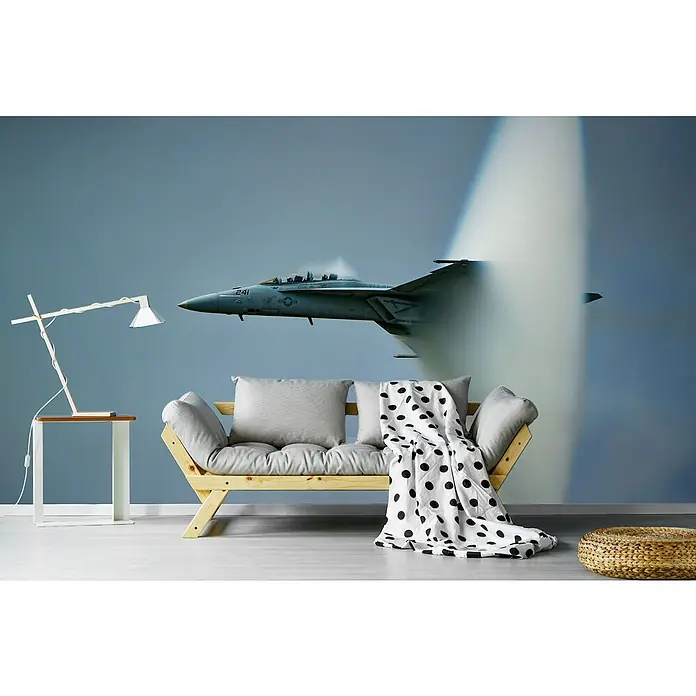Papermoon Premium collection Fototapete Kegel - B x H: 350 x 260 cm, Vlies - Moderne Couch mit Kissen und einer schwarz-weißen Decke, ergänzt durch eine stilvolle Lampe und einen Hocker, vor einer Wandtapete mit Flugzeugmotiv.