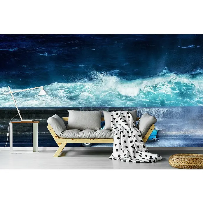 Papermoon Premium collection Fototapete Blaue Tour - B x H: 200 x 149 cm, Vlies - Ein stilvolles Wohnzimmer mit einer Couch, die mit einer gepunkteten Decke und Kissen dekoriert ist, vor einer Fototapete mit Meeresmotiven.