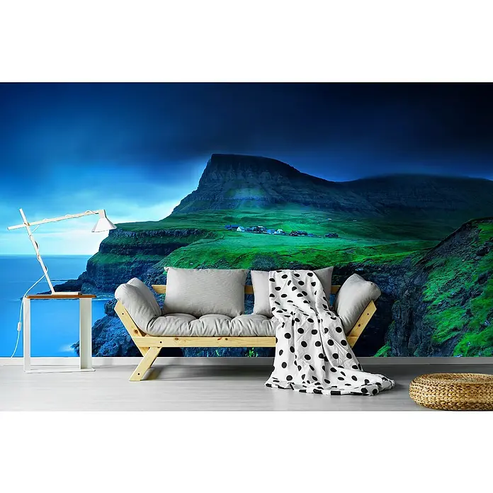 Papermoon Premium collection Fototapete Gasadalur - B x H: 500 x 280 cm, Vlies - Moderne Wohnzimmergestaltung mit einem skandinavischen Sofa, weichen Kissen und einer stilvollen Punktmuster-Decke vor einer dramatischen Bergkulisse.