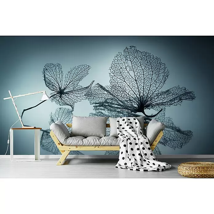 Papermoon Premium collection Fototapete Die Feinheit der Blume - B x H: 500 x 280 cm, Vlies - Ein gemütliches Holzsofa mit grauen Kissen und einer gepunkteten Decke in einem Raum mit Skelettblatt-Mural.